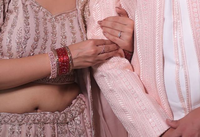 Bride's hand with red bangles on the groom's arm, sample photo